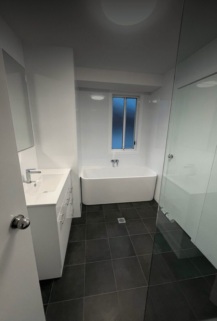 Modern bathroom with white fixtures and tiles.
