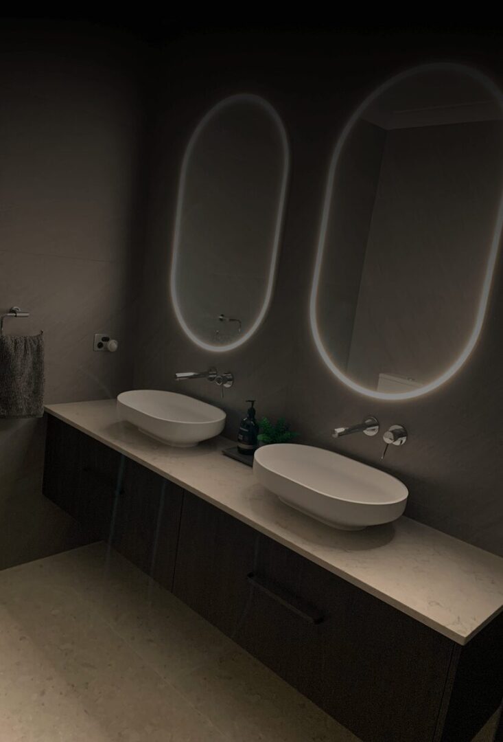 Modern bathroom with illuminated mirrors and sinks.